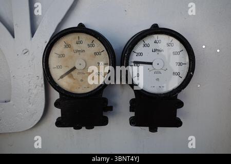 Gros plan de deux débitmètres analogiques vintage montés sur une machine industrielle. Banque D'Images