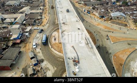 Vue aérienne d'un échangeur en béton nouvellement construit contrastant avec l'étalement urbain environnant, Port Harcourt, Rivers, Nigeria. Banque D'Images