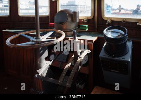 Gros plan du volant en bois vintage et des instruments de navigation sur le pont d'un bateau classique. Banque D'Images