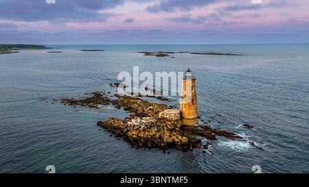 Whaleback Lighthouse est un phare solitaire debout sur un éperon rocheux entouré par la vaste étendue d'un océan calme sous un ciel peint de teintes Banque D'Images