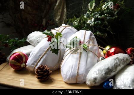 Pains Stollen enveloppés dans du papier blanc avec houx festif et ficelle rustique Banque D'Images
