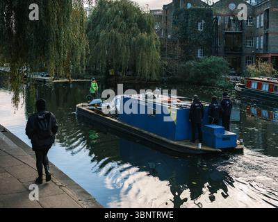 Royaume-Uni, Londres, 08 juillet 2025. Une barge de maintenance avec des ouvriers navigue Regent’s canal près des saules et des péniches amarrées dans un resi calme Banque D'Images