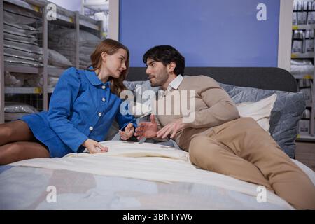 Un couple aimant est heureux de se détendre sur leur lit dans une configuration de chambre moderne magnifiquement conçu Banque D'Images