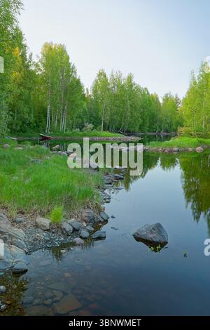 Ruisseau paisible avec de petits bateaux amarrés le long des rives à Utran saaret, Joensuu, Finlande, entouré de bouleaux Banque D'Images