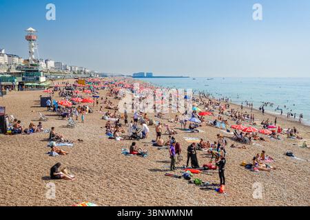 Les gens profitant d'une journée ensoleillée sur une plage à Brighton, East Sussex Angleterre Royaume-Uni Banque D'Images
