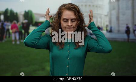 Femme exprimant la frustration devant la tour penchée de pise parmi les touristes dans un cadre urbain dynamique, capturant un mélange d'émotion et de t emblématique Banque D'Images