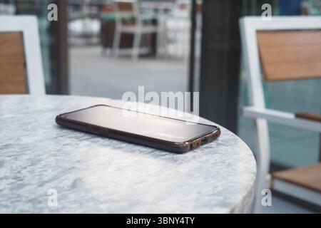 Smartphone reposant sur une table dans un cadre de café. concept de téléphone intelligent perdu Banque D'Images