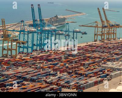 Des portiques bleus et jaunes s'élèvent au-dessus de piles de conteneurs maritimes dans le port très fréquenté de Barcelone, un important centre commercial européen, l'Espagne. Banque D'Images