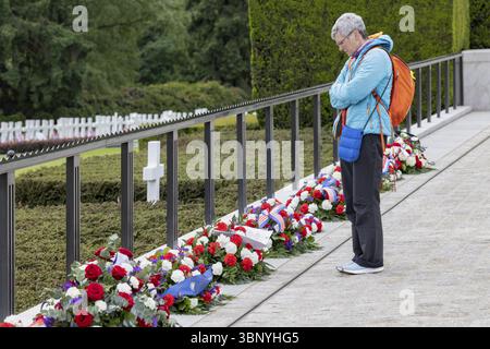 Une femme absorbée par la pensée devant des arrangements floraux dans un cimetière, Luxembourg American Cemetery and Memoria, Luxembourg, Grand-Duché de Luxembourg Banque D'Images