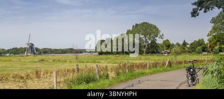 Vue panoramique du moulin de Helper et vélo le long de Patersolwdsemeer près de Groningen aux pays-Bas Banque D'Images