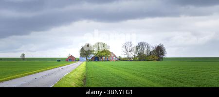 Ancienne ferme hollandaise typique avec ciel nuageux près de la digue à Groningen aux pays-Bas, Uithuizermeeden, Nederland Banque D'Images