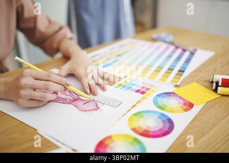 Créateur de mode artiste élégant ou créateur dessinant sur un carnet de croquis avec un nouveau projet de conception travaillant en studio Banque D'Images