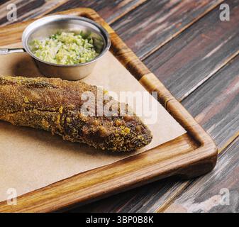 Nature morte, poisson frit sur planche de bois avec sauce épicée Banque D'Images