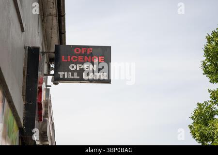 Enseigne néon indiquant « Off licence Open Till Late » avec texte rouge et blanc. Bien qu'éclairée, la photo a été prise en plein jour à l'extérieur du magasin. Banque D'Images