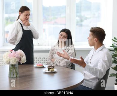 Couple se plaignant au serveur à propos du gâteau à table dans le restaurant Banque D'Images