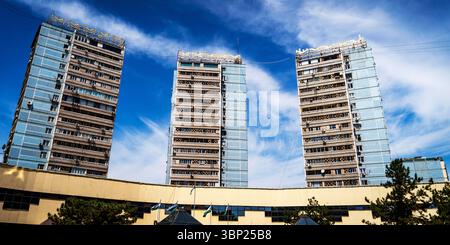 Trois gratte-ciel modernes avec des façades en verre contre un ciel bleu avec des nuages. Les bâtiments font partie d'une structure plus grande, montrant le mépris Banque D'Images
