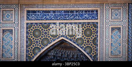 Une vue rapprochée de l'architecture islamique complexe avec des carreaux bleus et dorés, des motifs géométriques et la calligraphie arabe. Les vitrines de conception Banque D'Images
