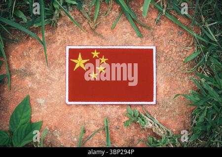 Drapeau de Chine brodé respectueux de l'environnement sur la pierre ancienne avec des feuilles naturelles, symbolisant le jour de la terre, le soin du climat et le patrimoine culturel. Banque D'Images