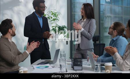 Femme d'affaires caucasienne femme gestionnaire des ressources humaines leader invitant homme d'affaires afro-américain nouvel employé de travailleur embaucher accueillant l'équipe amicale acclamant Banque D'Images