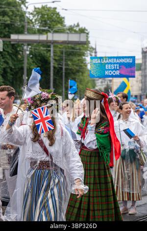 Participants aux costumes folkloriques agitant des drapeaux britanniques et estoniens, avec la bannière « USA Lääneranniku Eesti Koor », procession du Festival de la chanson à Tallinn Banque D'Images