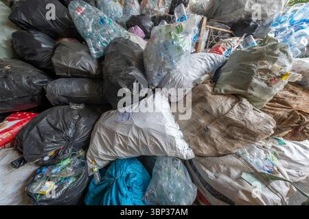 Nan, Thaïlande - 8 juin 2025 - énorme pile de sacs poubelle noirs, blancs et transparents remplis de bouteilles en plastique et d'autres déchets ménagers, illustrant un pol Banque D'Images