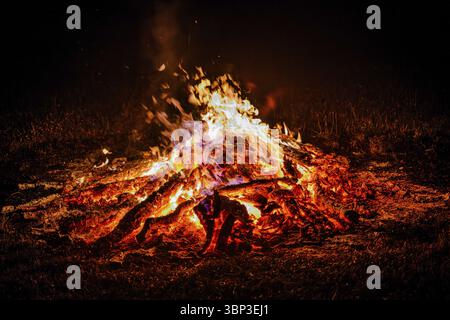 Un grand feu de camp avec des flammes brillantes sur une nuit sombre répand chaleur et lumière Banque D'Images