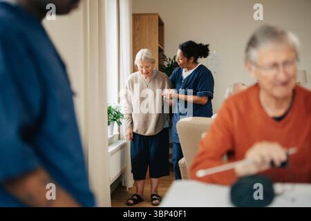 Aidante aidant une femme âgée à marcher dans une maison de retraite Banque D'Images