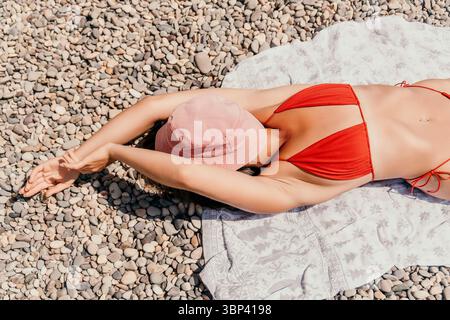 Femme plage serviette de bain de soleil Red Bikini Hat Pebble Banque D'Images