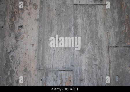 Un gros plan de la texture du mur en béton, montrant son aspect rugueux et usé avec des fissures visibles et des éclats de peinture Banque D'Images