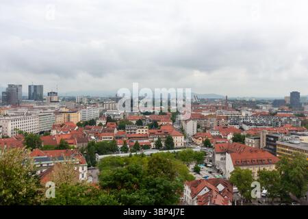 Une vaste vue surélevée capture le paysage urbain de Ljubljana, Slovénie, par temps nuageux. Les toits en tuiles rouges dominent le premier plan, mettant en valeur le Banque D'Images