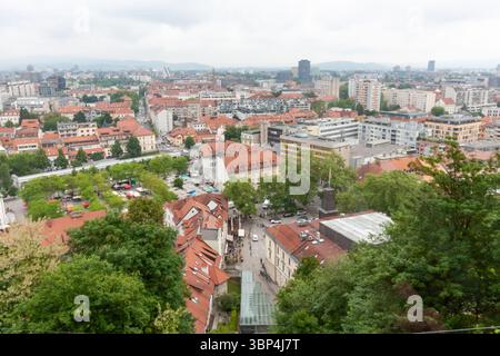 Une vaste vue surélevée capture le paysage urbain de Ljubljana, Slovénie, par temps nuageux. Les toits en tuiles rouges dominent le premier plan, mettant en valeur le Banque D'Images