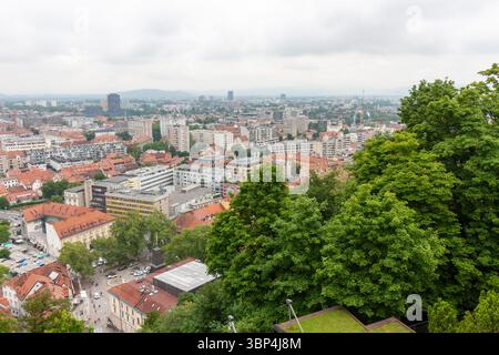 Une vaste vue surélevée capture le paysage urbain de Ljubljana, Slovénie, par temps nuageux. Les toits en tuiles rouges dominent le premier plan, mettant en valeur le Banque D'Images