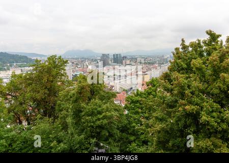 Une vaste vue surélevée capture le paysage urbain de Ljubljana, Slovénie, par temps nuageux. Les toits en tuiles rouges dominent le premier plan, mettant en valeur le Banque D'Images
