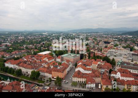 Une vaste vue surélevée capture le paysage urbain de Ljubljana, Slovénie, par temps nuageux. Les toits en tuiles rouges dominent le premier plan, mettant en valeur le Banque D'Images