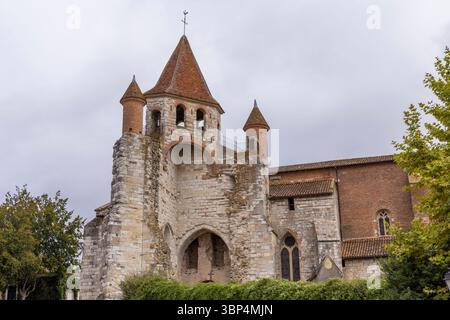 L'imposante église notre Dame de l'Assomption se dresse haute contre un ciel nuageux, mettant en valeur son mélange unique de styles architecturaux à Auvillar Banque D'Images