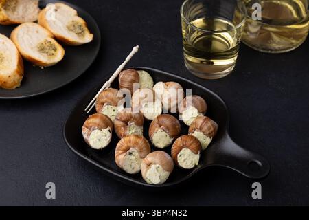 Escargot bourguignon au beurre et à l'ail. Plat traditionnel français à base d'escargots, servi avec baguette et vin blanc. Mise au point sélective, gros plan, Banque D'Images