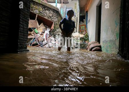 (250706) -- BOGOR, 6 juillet 2025 (Xinhua) -- Un garçon patère dans l'eau de crue après de fortes pluies dans la régence de Bogor, Java occidental, Indonésie, le 6 juillet 2025. Trois personnes ont été tuées, une est portée disparue et huit autres ont été blessées après des glissements de terrain qui ont frappé la province indonésienne de Java occidental samedi après-midi, selon Hadi Rahmat Hardjasasmita, porte-parole de l'Agence provinciale de gestion et d'atténuation des catastrophes dimanche. Déclenchés par de fortes pluies, les glissements de terrain ont frappé plusieurs zones de la régence de Bogor vers 18 h, heure locale, samedi, endommageant environ huit maisons. (Photo de R Banque D'Images