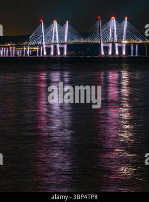 Nyack, NY - US - Jul 2, 2025 le pont lumineux Tappan Zee brille la nuit, projetant des reflets vibrants de violet, rouge et blanc à travers l'Hudson Banque D'Images