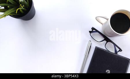 Espace de travail minimaliste à plat avec plante, lunettes, stylo, cahier et une tasse de café sur blanc. Idéal pour les affaires, la planification, la productivité, tim Banque D'Images