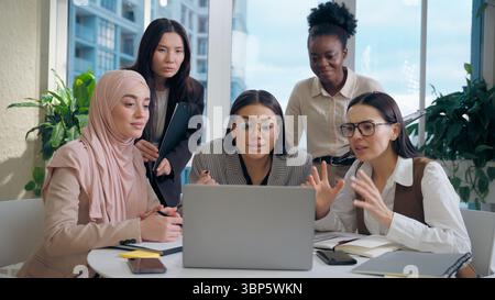 Excité choqué multiethnique femmes femmes d'affaires collègues groupe multiracial cherchant ordinateur portable célébrant l'offre d'affaires de choc gagnant Banque D'Images