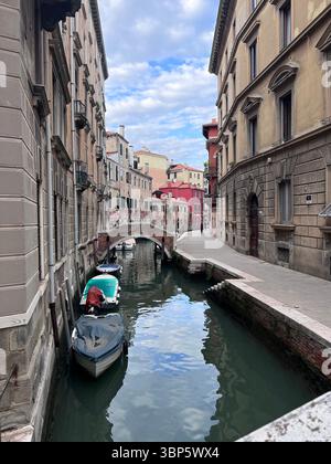 Croisière traditionnelle à travers un canal étroit à Venise, en Italie, entouré de bâtiments historiques et reflétant le charme de cette ville d'eau emblématique Banque D'Images