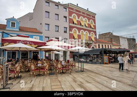 Porec, Croatie - 21 mai 2025 : les gens se promènent dans la rue centrale médiévale historique de la vieille ville avec des restaurants par temps pluvieux. Banque D'Images