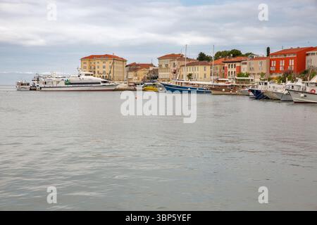 Porec, Croatie - 21 mai 2025 : Port pittoresque avec des bateaux amarrés et des yachts le long de la côte adriatique, entouré de bâtiments historiques colorés. Peacefu Banque D'Images