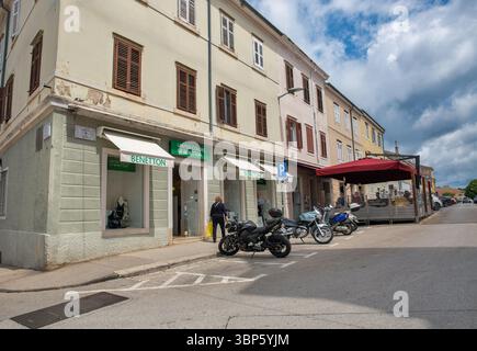 Porec, Croatie - 21 mai 2025 : rue historique dans la vieille ville avec l'architecture traditionnelle d'Istrie avec magasin de vêtements Benetton, motos garées Banque D'Images