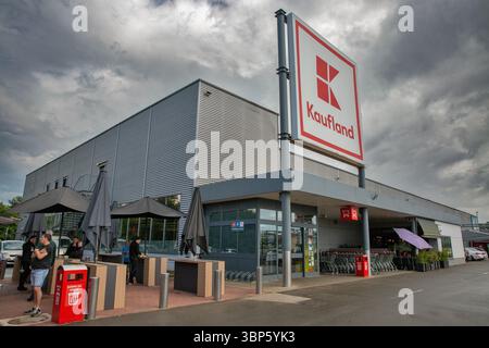 Porec, Croatie - 21 mai 2025 : supermarché moderne Kaufland avec façade métallique, grande signalisation, chariots et personnes debout sous parapluies Banque D'Images