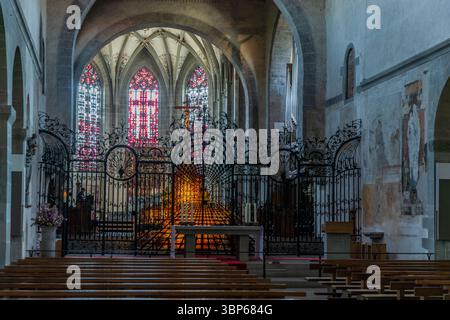 Une vue de l'intérieur de St Mary et St Marc's Minster sur l'île de Reichenau, Bade-Württemberg, Allemagne. La photo montre la zone de l'autel avec une grille en fer forgé ornée, une statue de la Vierge Marie, des peintures murales historiques et un vitrail lumineux ou reliquaire, créant une atmosphère spirituelle dans ce site classé au patrimoine mondial de l'UNESCO. Münsterplatz, Reichenau, Bade-Württemberg, Allemagne Banque D'Images