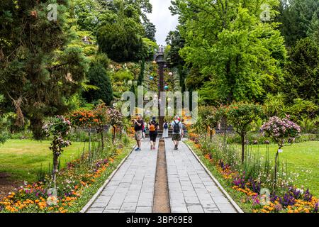 Les visiteurs explorent le magnifique jardin en terrasses sur l'île de Mainau sur le lac de Constance près de Constance, en Allemagne. Ils apprécient la splendeur florale variée, les grands arbres, les caractéristiques aquatiques de l'escalier d'eau de fleurs italiennes et les boules colorées décoratives qui ornent le terrain Banque D'Images