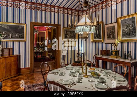 Une salle à manger ou un salon historique dans le château d'Arenenberg à Salenstein, Thurgau, Suisse, est représenté ici. La pièce, caractérisée par son papier peint rayé, ses meubles anciens et ses tableaux encadrés, montre une table posée avec de la vaisselle fine. Il donne un aperçu du mode de vie des anciens résidents, comme Hortense de Beauharnais et son fils Louis Napoléon Banque D'Images