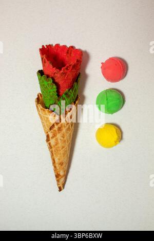 Cônes multicolores et cuillères à crème glacée sur fond gris. Couleurs éclatantes Banque D'Images