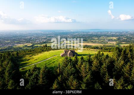 Vue aérienne de la ruine du Hell Fire Club entourée de forêt, avec vue sur Dublin s'étendant à travers l'horizon lointain Banque D'Images